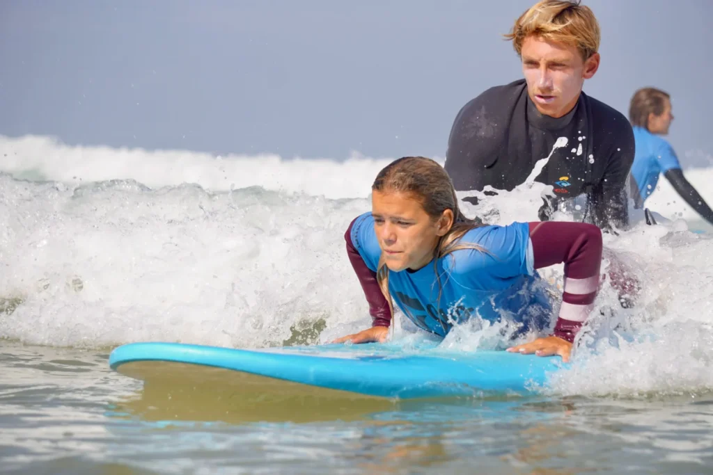 Hugo qui pousse un surfer débutant