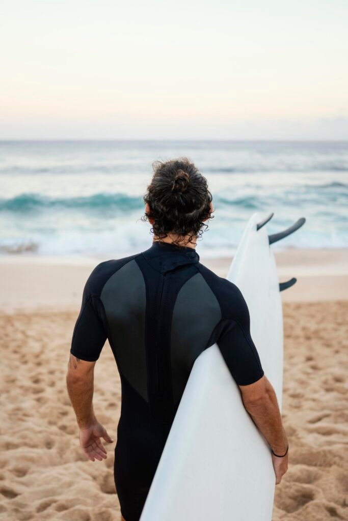 Homme portant des vêtements de surfeur marchant sur le sable