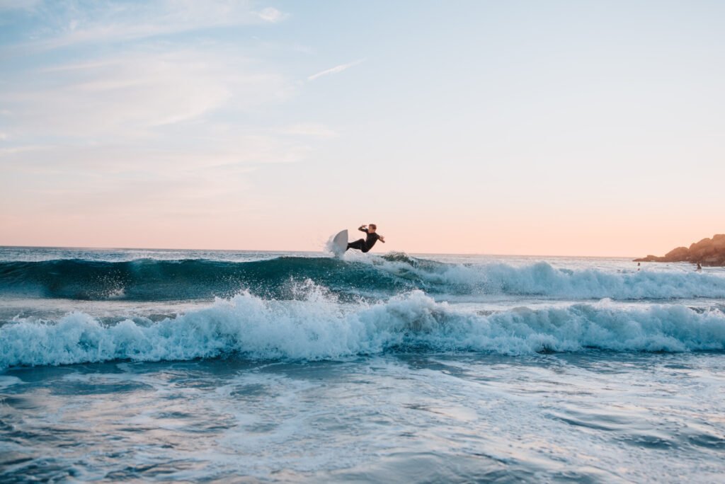 Jeune garçon latino faisant des tours de surf tout en attrapant les vagues au coucher du soleil. Espace de copie